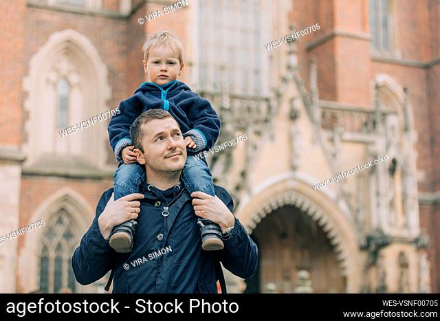 Father carrying son on shoulders in front of cathedral