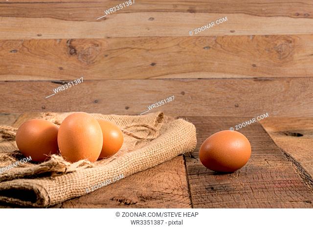 Easter background with brown organic eggs arranged on burlap sack on rustic wooden table