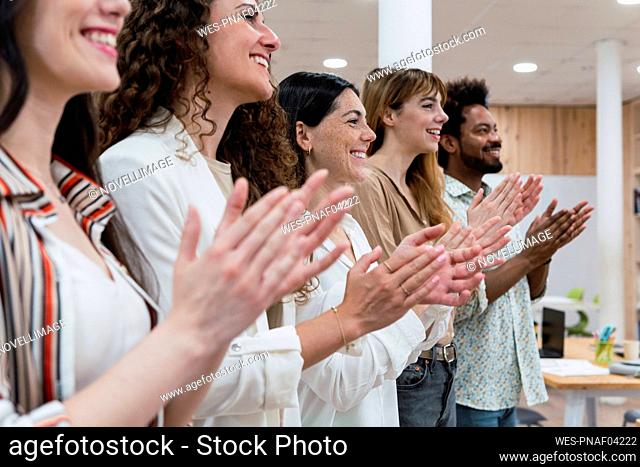 Happy business team clapping hands after a presentation in office