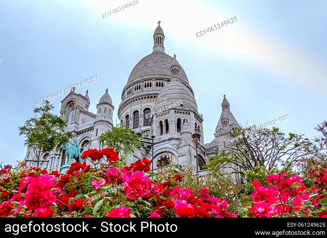 France. Cloudy evening near Sacre Coeur Cathedral in Paris. Flowerbed with red roses in the foreground