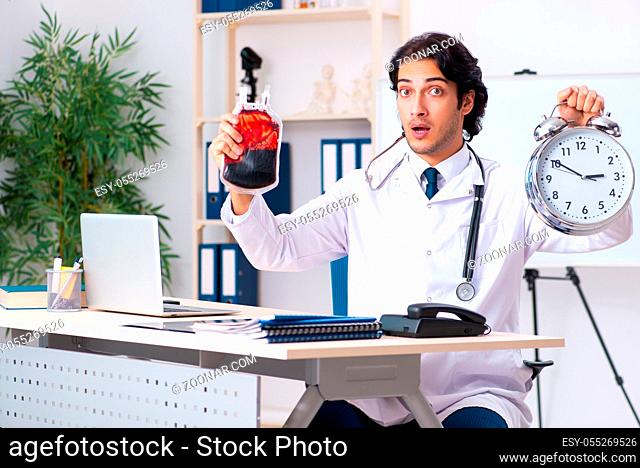Young handsome doctor in blood transfusion concept