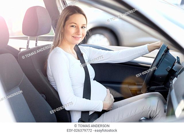 Pregnant woman driving her car, wearing seat belt