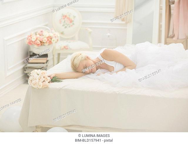Bride sleeping on bed with bouquet of flowers