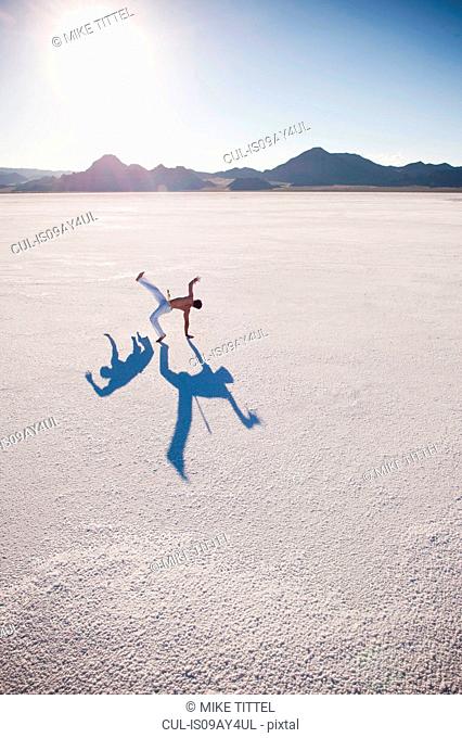 Man with two shadows performing capoeira on Bonneville Salt Flats, Utah, USA