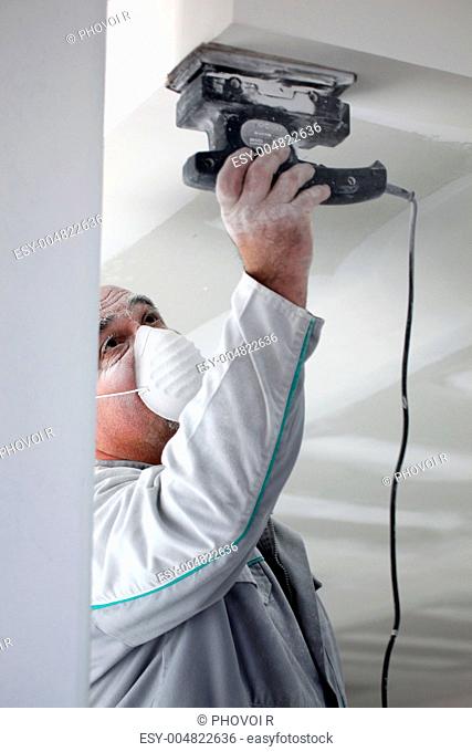 Decorator sanding a plaster ceiling