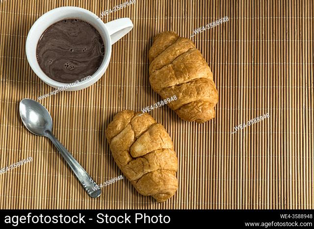 Cup of chocolate and croissant on a mat