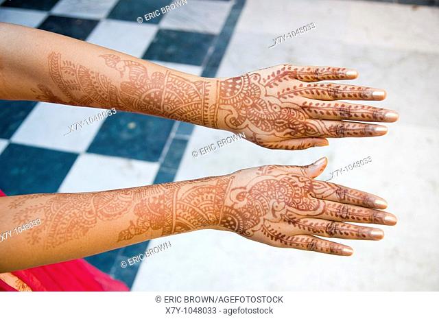 A new bride holds out her hands that are decorated in henna tattoos