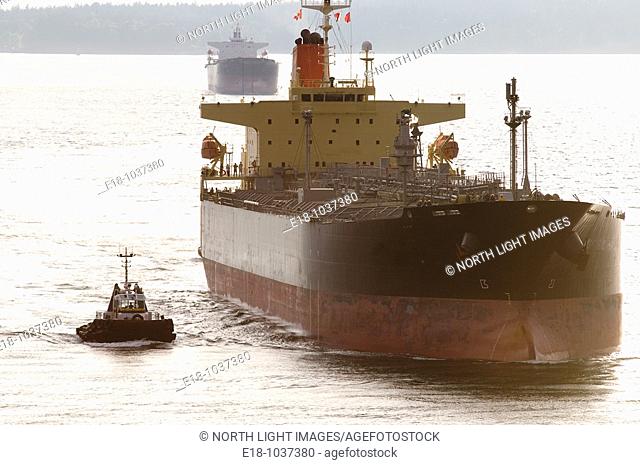 Canada, BC, Vancouver Freighter is escorted in the Burrard Inlet by harbour tugs