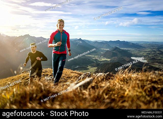 Sports people practicing trail running on mountain path of Saulingspitze at Bavaria, Germany
