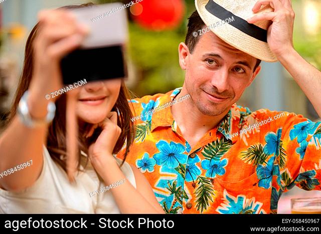 Portrait of young tourist man and young Asian tourist woman together at restaurant in the city outdoors