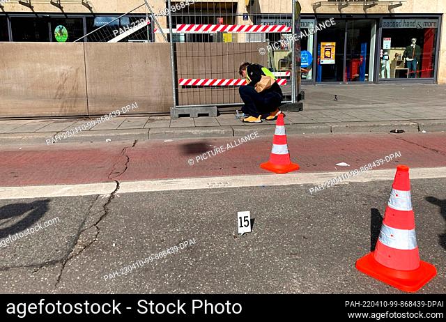 10 April 2022, Munich: A policewoman secures evidence after a homicide in the city center. Early Sunday morning, a man was stabbed during an argument there