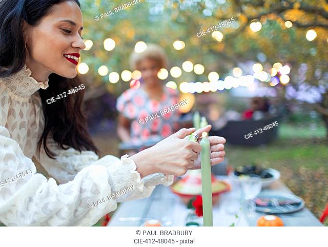 Woman lighting candles for dinner garden party