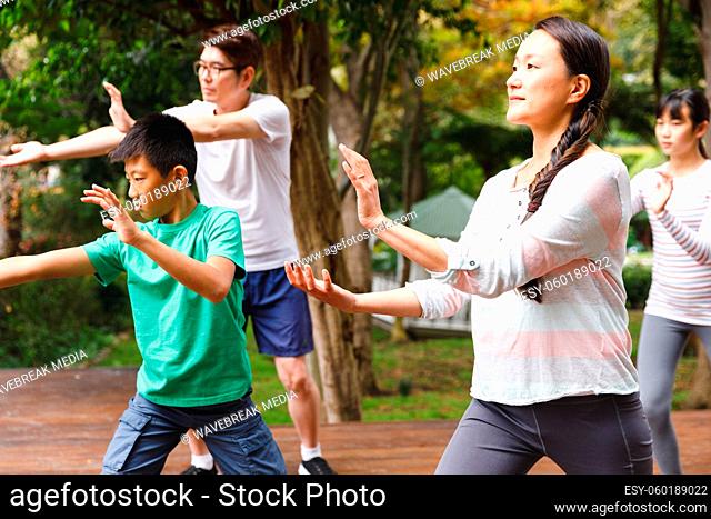 Asian parents, son and daughter exercising outdoors, practicing tai chi
