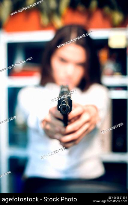 Close up of gun in ladys hands. Close up picture of gun being held by woman dressed in white blouse blurred in background