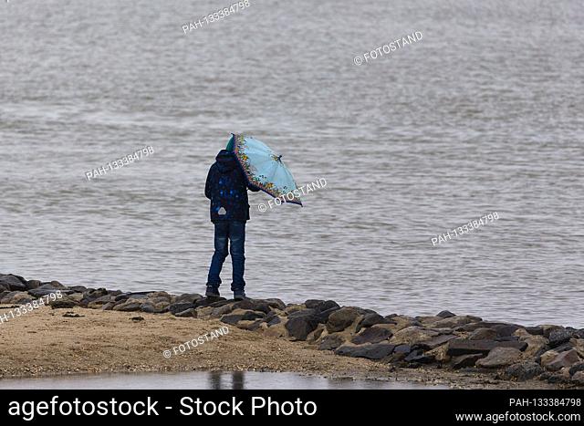 Harlesiel / Carolinensiel, Germany June 2020: Symbol pictures - 2020 A little boy stands in the rain with his umbrella at the pier in Carolinensiel-Harlesiel