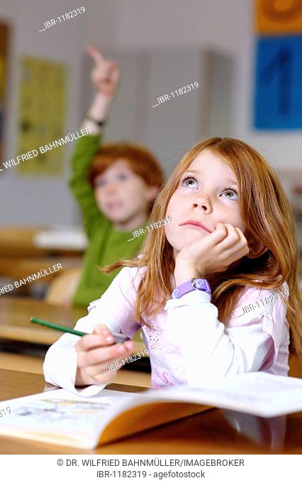 Children in a classroom in primary school, girl daydreaming or looking unsure, thoughtful, sad or frustrated, equal oppurtunity in the education system