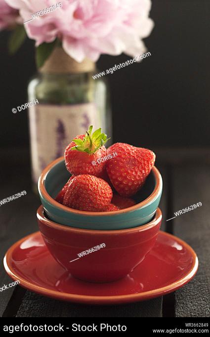 Bowl of strawberries on wooden table, close up