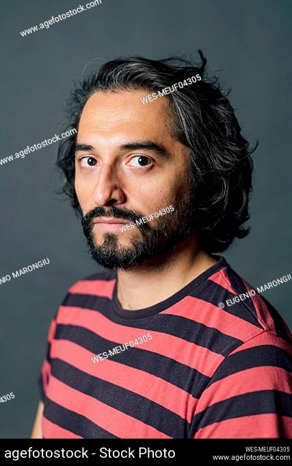Confident man with black hair wearing striped t-shirt