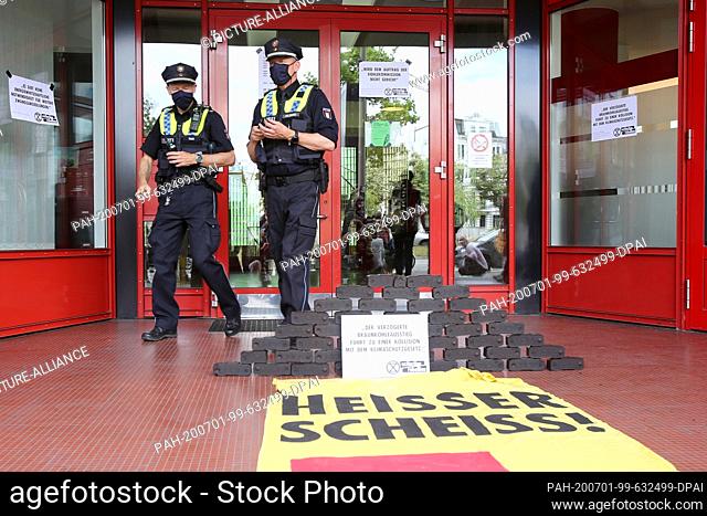 01 July 2020, Hamburg: With briquettes and banners, among other things with the inscription ""Heisser Scheiss!"" (hot shit) activists protest in front of the...