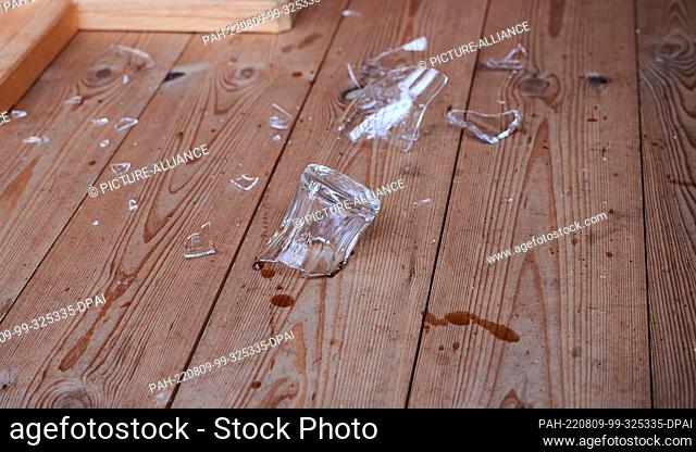 PRODUCTION - 01 August 2022, Austria, Mayrhofen: ILLUSTRATION - A glass broken into shards lies on a wooden floor. (posed scene) Photo: Annette Riedl/dpa
