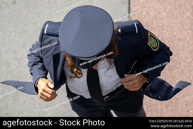 29 September 2023, Saxony, Dresden: A policewoman puts on her jacket in front of the Palace of Culture before the ceremonial appointment of 213 commissioners of...