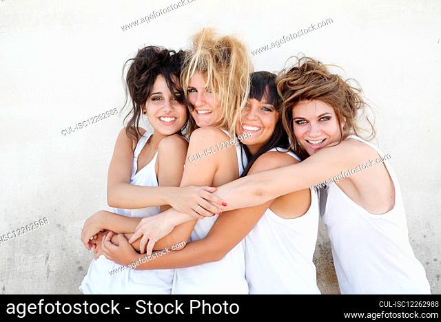 Portrait of four young women having fun, hugging and smiling at camera