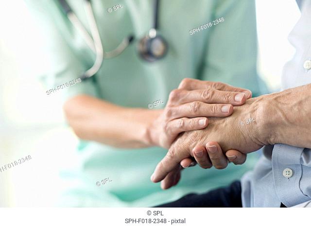 Care worker holding senior man's hand