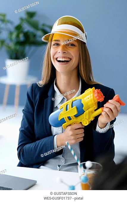 Laughing, young businesswoman, holding water gun