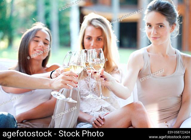 Happy female friends toasting white wine outdoors