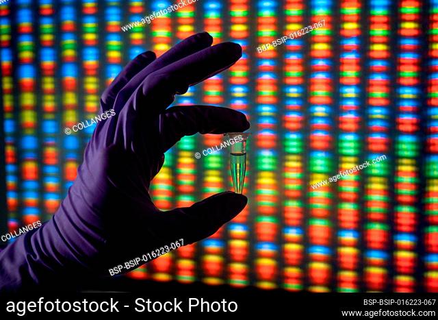 Hand holding a tube of DNA samples in front of a picture of a genome