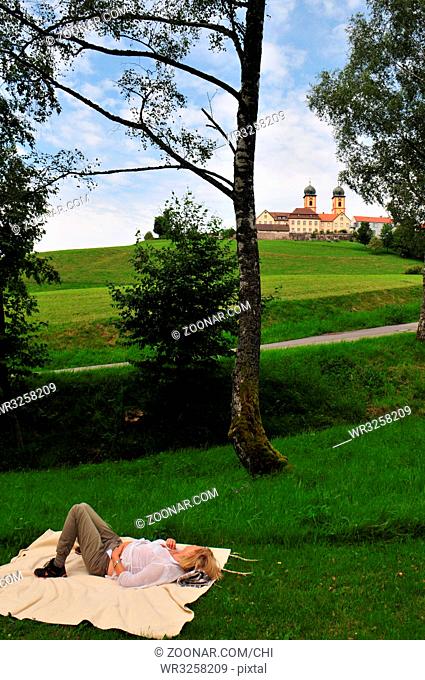 Frau liegt auf einer Decke im Gras im Schwarzwald zwischen Bäumen. Die Kneippanlage und die Landschaft bei St. Märgen im Schwarzwald laden zum Wasssertreten