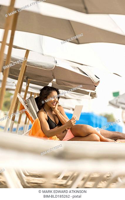 African American woman using digital tablet on beach