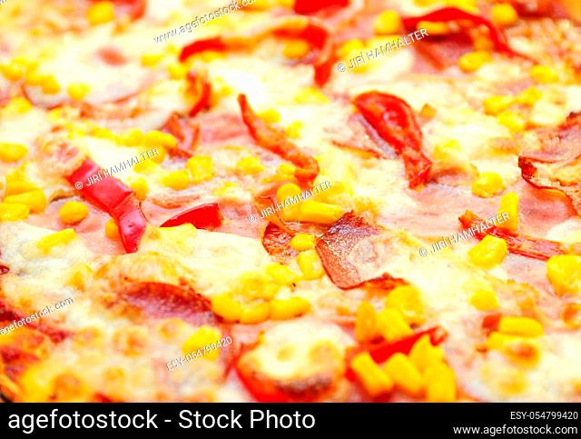 A closeup of pizza surface with ham, salami, cheese and red pepper. Full frame background shot of pizza, selective focused on foreground