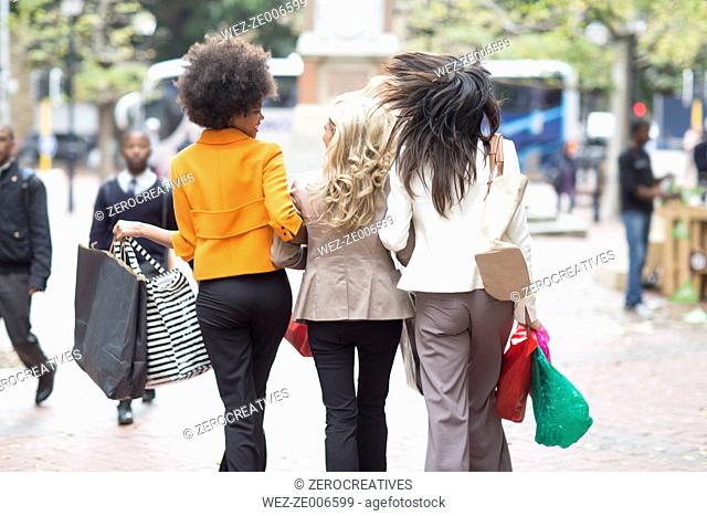 Back view of three women side by side on shopping tour