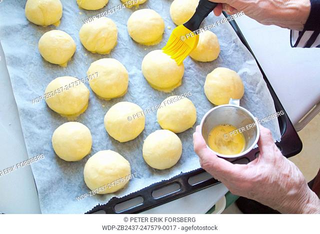 Butter is put on raw sweet rolls, before going into oven on tray, baking, Finland, Europe