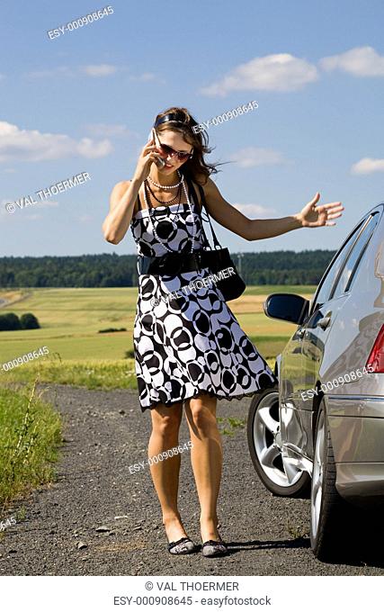 woman talking by mobile phone beside the car
