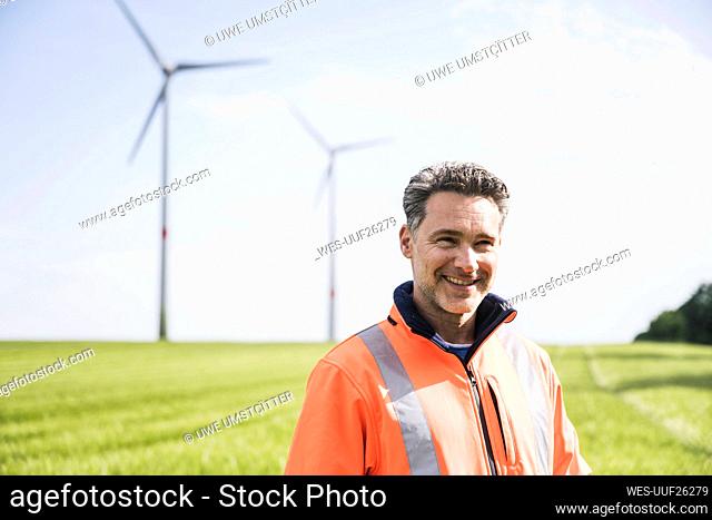 Smiling engineer standing in field on sunny day