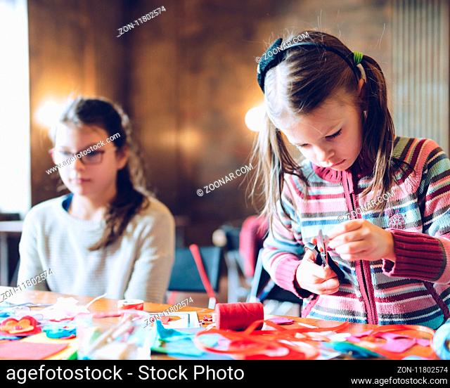tailor art workshops for children - a girl sewing felt decorations - colorful fabrics lying on a table
