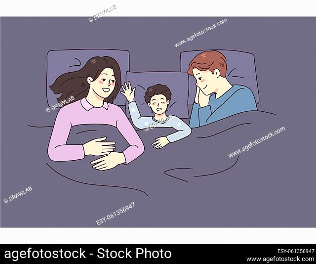 Happy young family with small kid sleep together in bed at home. Smiling parents relax take nap with little child. Childcare and parenthood concept