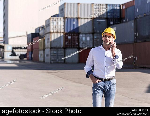 Businessman on the phone wearing safety helmet at industrial site
