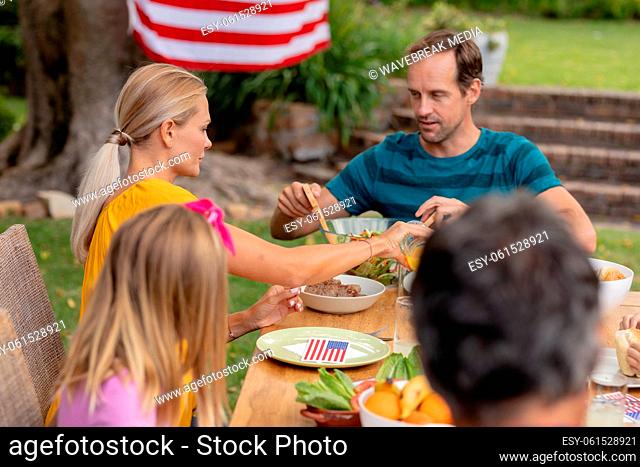 Caucasian man serving family before eating meal together in garden