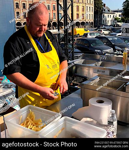 07 October 2023, France, Arras: Gastronome Paul-Henri Doumenc prepares French fries. Dozens of frites gastronomes compete against each other on the Great Square...