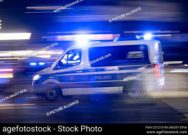 18 December 2023, Saxony, Dresden: A police car with flashing blue lights drives across the Augustus Bridge at the edge of a demonstration of the right-wing...