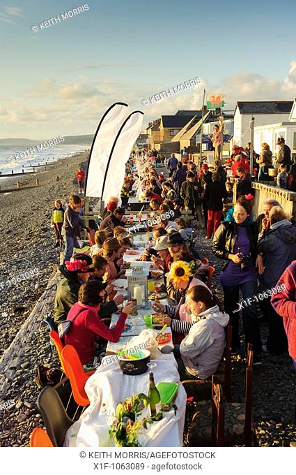 People sitting at tables at the annual al fresco dinner on the beach, summer evening, Borth village, Ceredigion Wales ULK