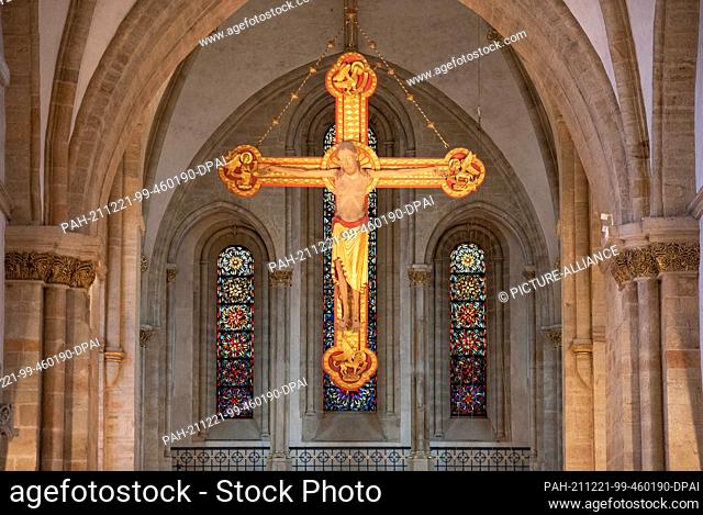 PRODUCTION - 17 December 2021, Lower Saxony, Osnabrück: A large cross hangs in the Catholic cathedral of Osnabrück. A nativity scene with 46 figures stands in...