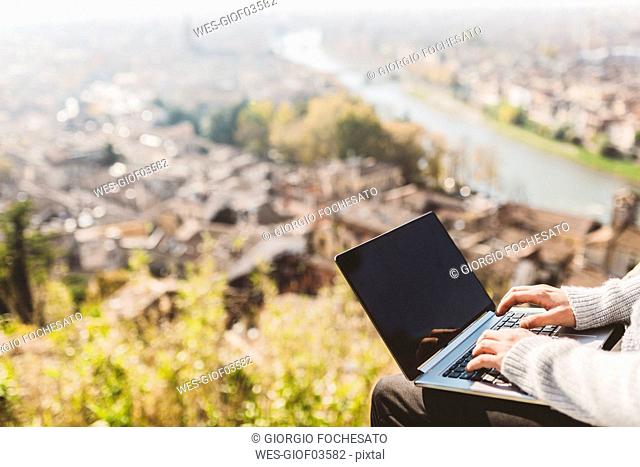 Italy, Verona, tourist using laptop, observation point