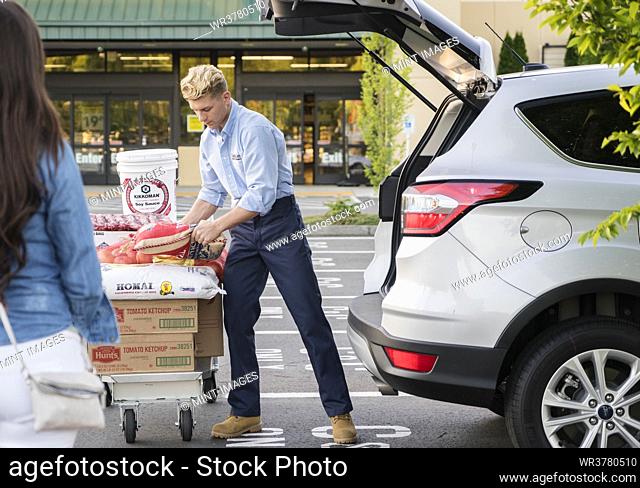 Couple loading groceries from wholesaler into the trunk of a car