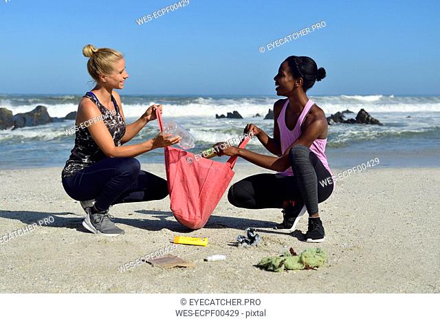Two women cleaning the beach from plastic waste