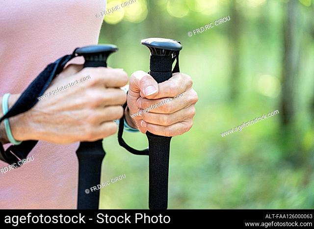 Mid section of mature woman holding hiking poles