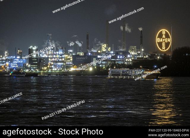20 November 2023, NoW, Cologne: A ship sails past the Bayer Group plant in the Chempark in the evening. Bayer has discontinued a study with an important drug...